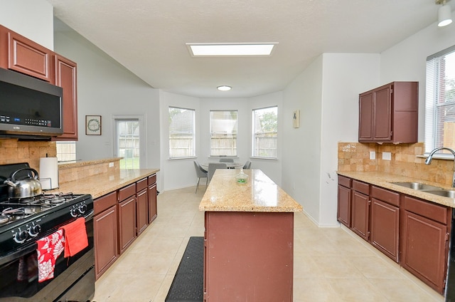 kitchen featuring a center island, sink, tasteful backsplash, light stone counters, and black range with gas cooktop