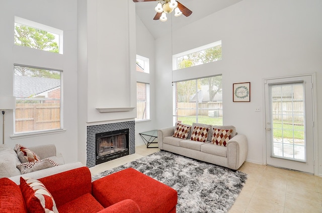 living room with a tile fireplace, a wealth of natural light, ceiling fan, and a high ceiling