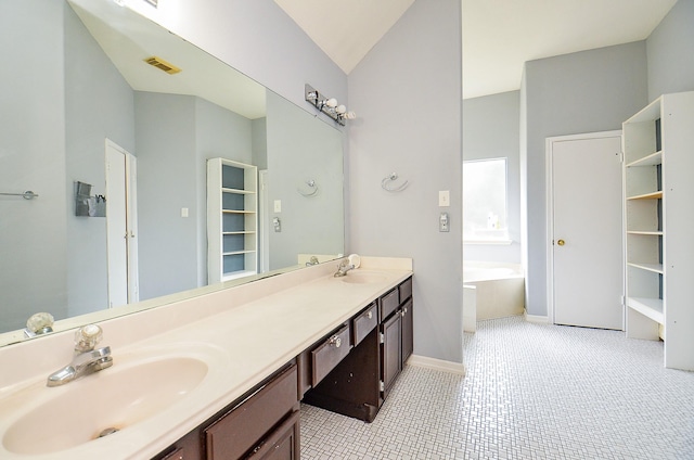 bathroom featuring tile patterned floors, a tub, vanity, and lofted ceiling