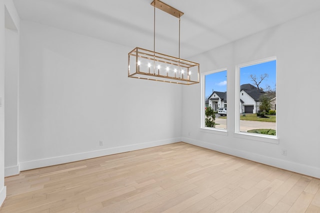 unfurnished dining area featuring light hardwood / wood-style flooring and an inviting chandelier