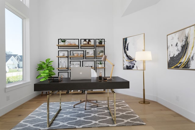 home office with hardwood / wood-style floors and a high ceiling