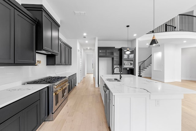 kitchen with light stone countertops, sink, stainless steel appliances, a spacious island, and pendant lighting