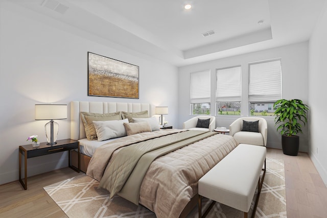 bedroom featuring a tray ceiling and light hardwood / wood-style flooring