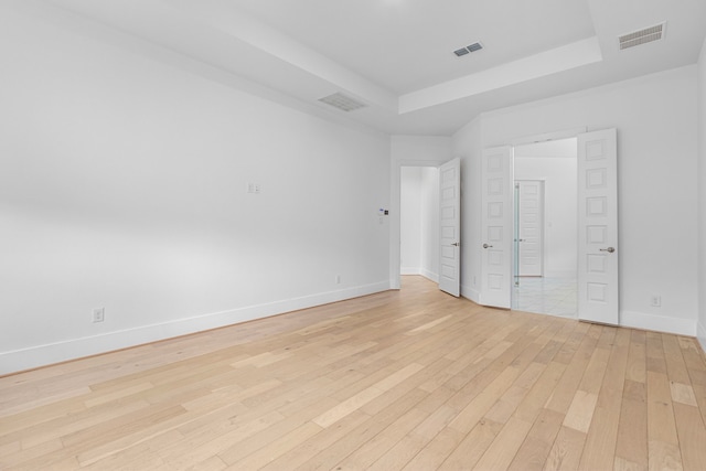 unfurnished room with light hardwood / wood-style floors and a raised ceiling