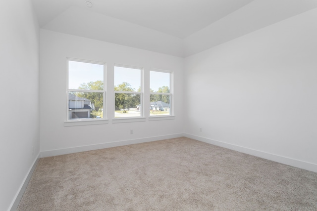 carpeted empty room featuring lofted ceiling