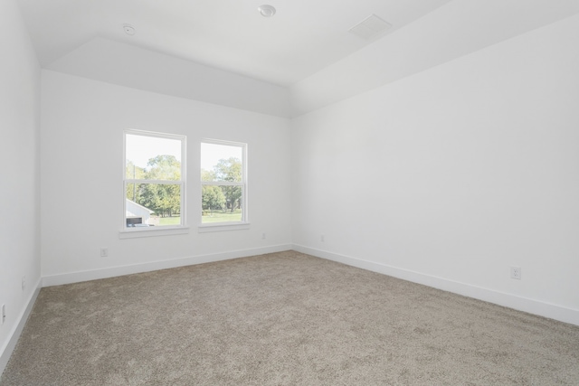 carpeted empty room featuring vaulted ceiling