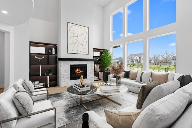 living room with a fireplace, a towering ceiling, and light hardwood / wood-style flooring