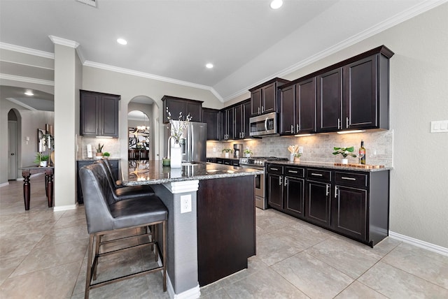 kitchen with a kitchen bar, stainless steel appliances, vaulted ceiling, sink, and a center island with sink