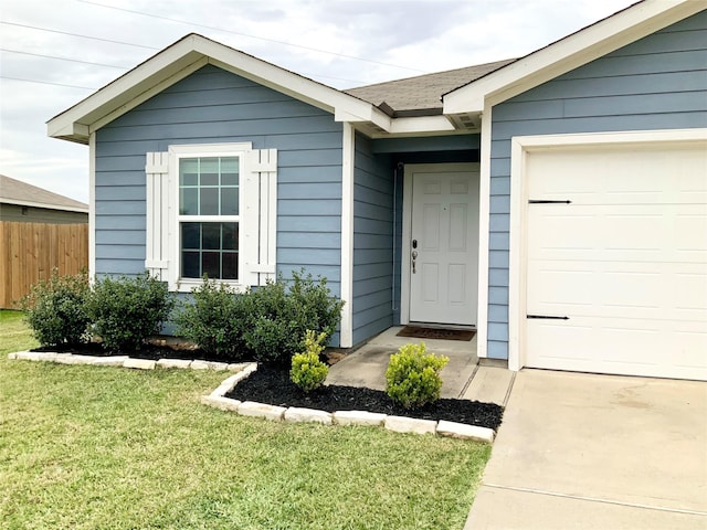 view of exterior entry with a garage and a lawn