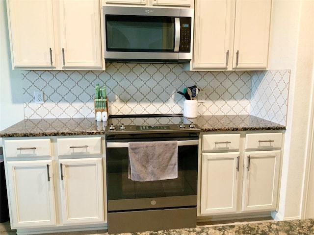 kitchen with backsplash, stainless steel appliances, dark stone counters, and white cabinets