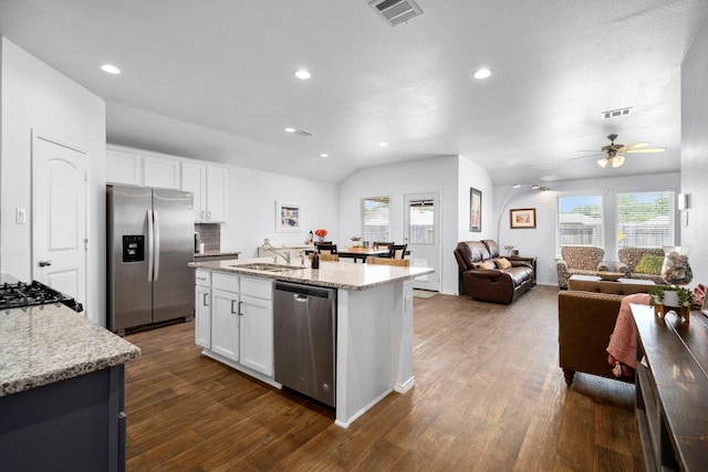 kitchen featuring light stone countertops, white cabinetry, sink, stainless steel appliances, and a center island with sink