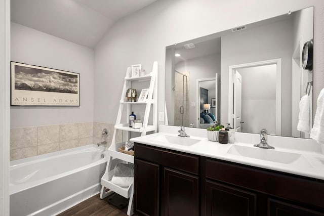 bathroom featuring vanity, wood-type flooring, vaulted ceiling, and shower with separate bathtub