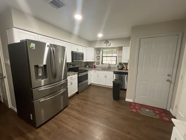 kitchen with white cabinets, appliances with stainless steel finishes, dark hardwood / wood-style floors, and sink