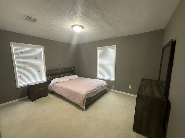 bedroom featuring a textured ceiling and light carpet