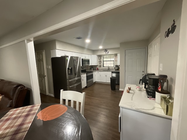 kitchen with light stone countertops, sink, dark wood-type flooring, white cabinets, and appliances with stainless steel finishes