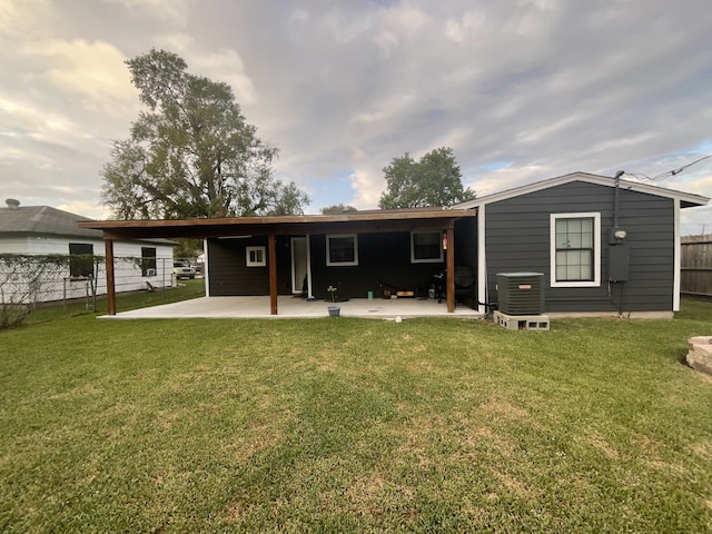 rear view of house featuring a yard, central AC unit, and a patio area