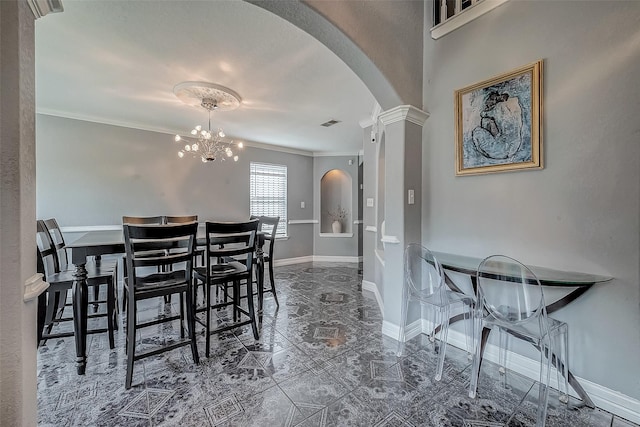 dining room with a chandelier, ornate columns, and ornamental molding