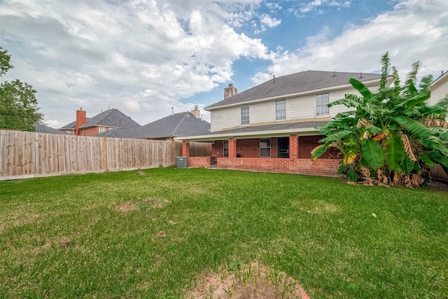 rear view of house with a yard and central AC