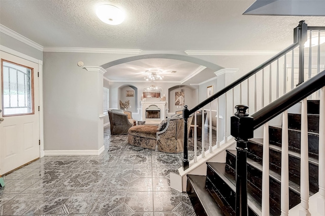 foyer entrance featuring a textured ceiling, decorative columns, and crown molding