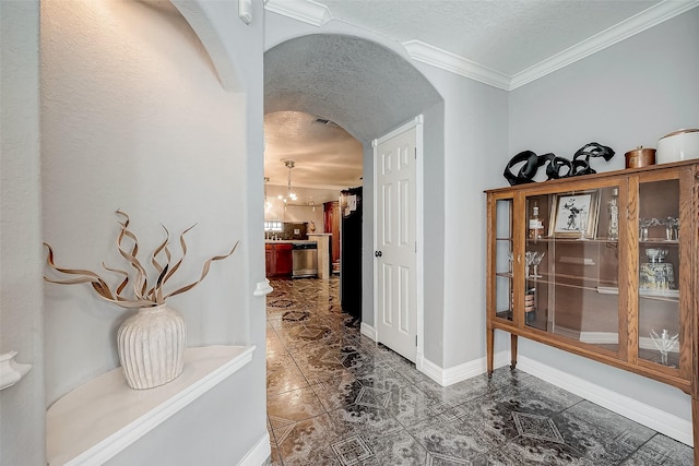 hall featuring a chandelier, a textured ceiling, and crown molding