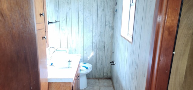 bathroom featuring tile patterned floors, vanity, toilet, and wooden walls