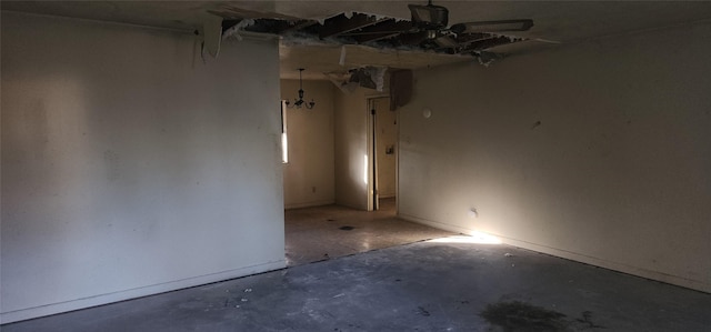 spare room with concrete flooring and a chandelier