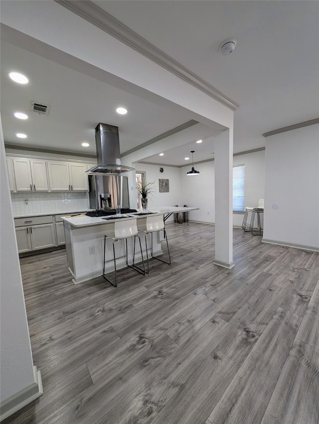 kitchen featuring a kitchen bar, island exhaust hood, a kitchen island, and hanging light fixtures