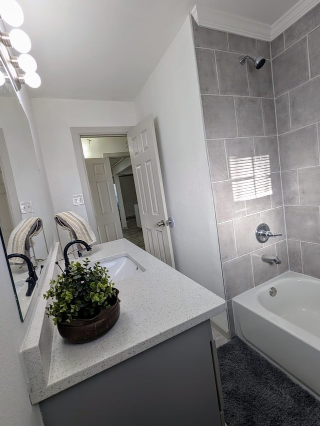 bathroom with vanity, ornamental molding, and tiled shower / bath combo