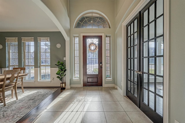 tiled entryway with crown molding, french doors, and a high ceiling