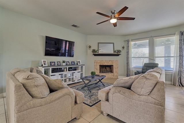 tiled living room featuring ceiling fan and a tiled fireplace