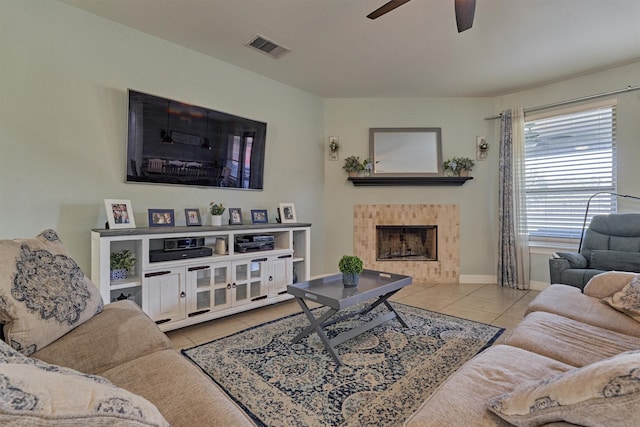 living room with a tiled fireplace, ceiling fan, and light tile patterned floors