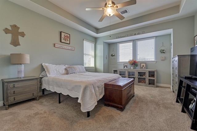 bedroom with a raised ceiling, ceiling fan, and light carpet