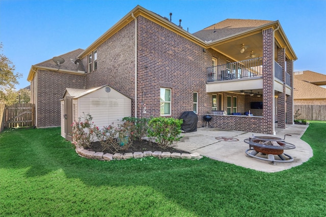 back of house featuring a fire pit, a lawn, a balcony, a storage unit, and a patio area