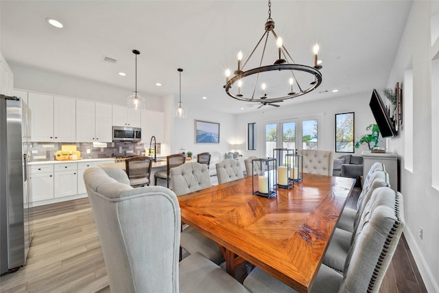 dining area with french doors, an inviting chandelier, and light wood-type flooring