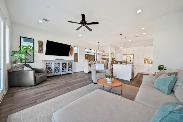 living room featuring sink, dark wood-type flooring, and ceiling fan with notable chandelier