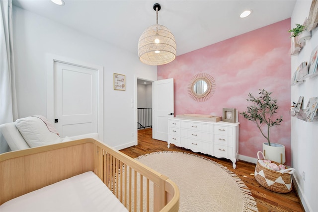 bedroom featuring a nursery area and hardwood / wood-style flooring