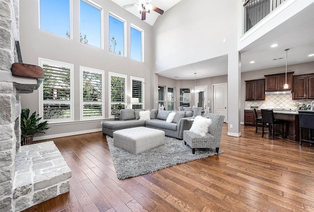 living room featuring ceiling fan, dark wood-type flooring, and a towering ceiling