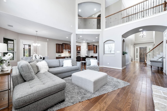 living room with dark wood-type flooring, a chandelier, and a high ceiling