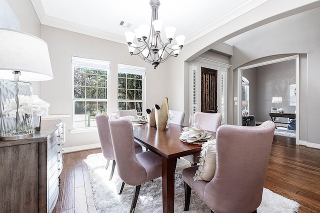 dining room with crown molding, dark hardwood / wood-style floors, and an inviting chandelier