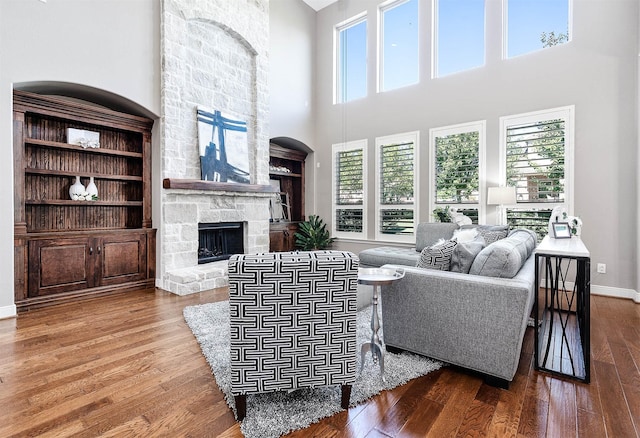 living room featuring a fireplace, a towering ceiling, and hardwood / wood-style flooring