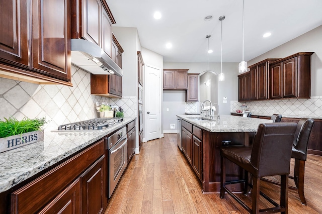 kitchen featuring a breakfast bar, pendant lighting, appliances with stainless steel finishes, and dark brown cabinetry