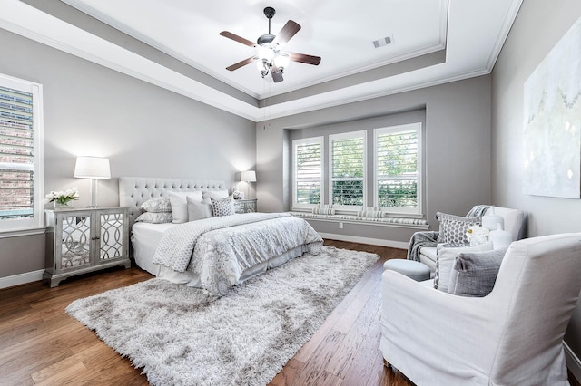 bedroom with ceiling fan, crown molding, hardwood / wood-style flooring, and a raised ceiling