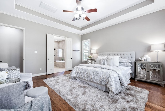 bedroom featuring ceiling fan, dark wood-type flooring, a tray ceiling, and ensuite bathroom