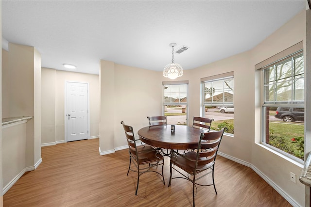 dining room with light hardwood / wood-style flooring and a chandelier