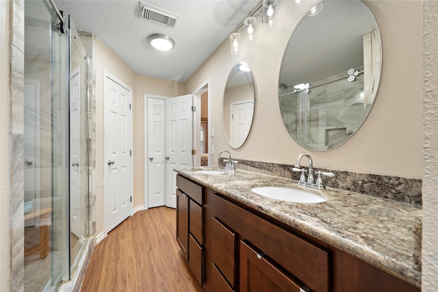 bathroom featuring a shower with door, vanity, a textured ceiling, and hardwood / wood-style floors