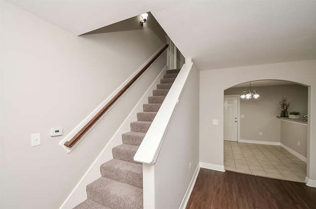 stairway featuring hardwood / wood-style floors and a notable chandelier