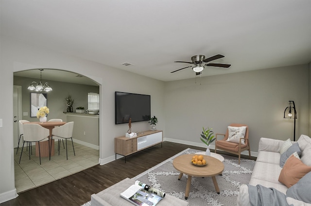 living room with ceiling fan with notable chandelier and hardwood / wood-style flooring