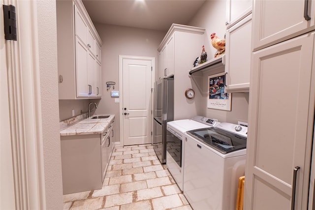 laundry room featuring washer and dryer, sink, and cabinets