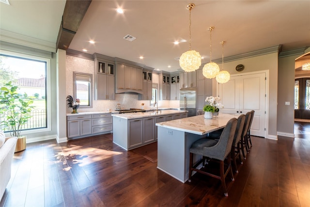 kitchen featuring pendant lighting, dark hardwood / wood-style floors, gray cabinetry, and a kitchen island with sink