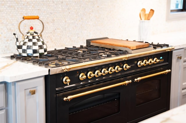 kitchen featuring decorative backsplash, double oven range, and light stone counters